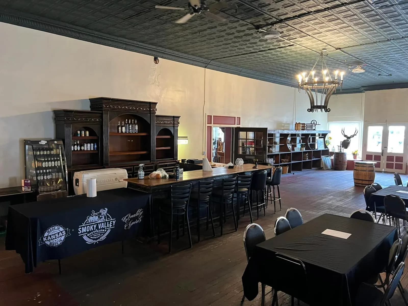 The main tasting room at Smoky Valley Distillery set with tables under a chandelier