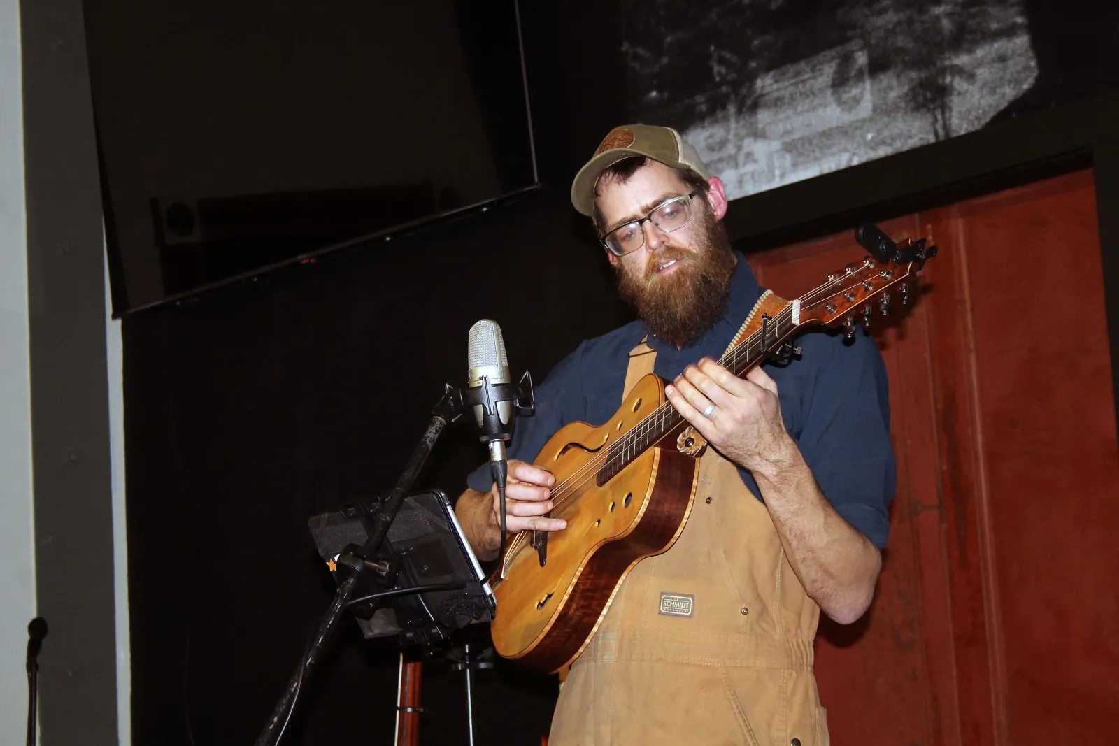 A musician playing mandolin on stage at Smoky Valley Distillery