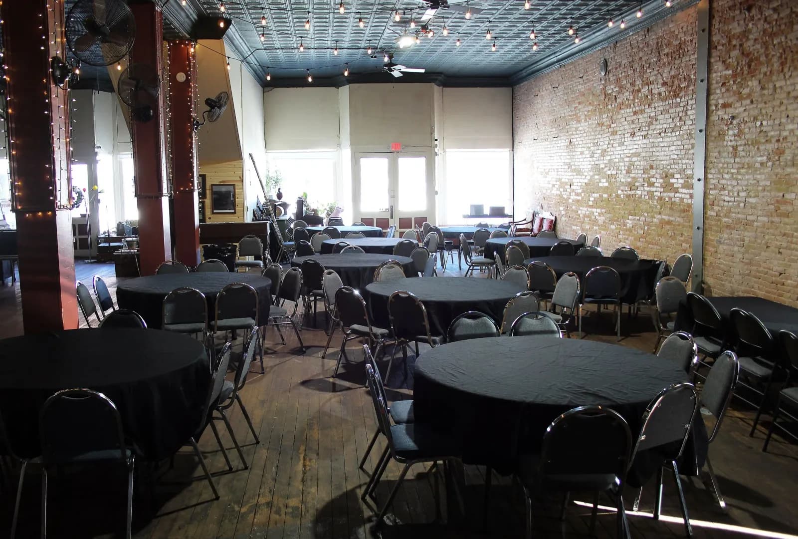 Round tables set with linens for a reception in the venue room at Smoky Valley Distillery